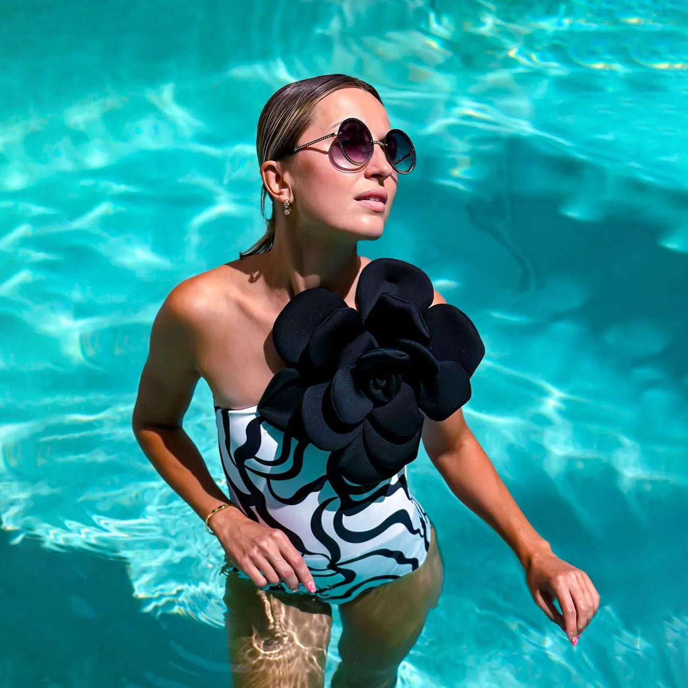 Black one-piece swimsuit with three-dimensional white floral pattern on a mannequin.