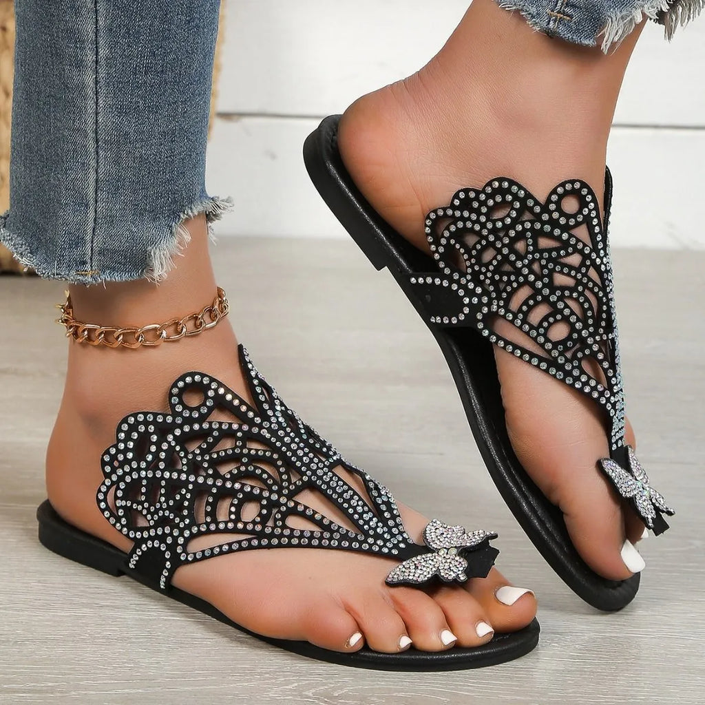 Women's black slip-on sandals with rhinestone decoration and a flip-toe design on a flat rubber sole.