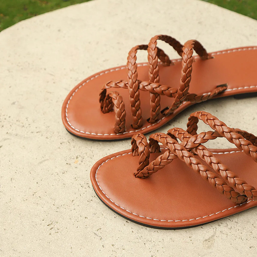 Women's woven clip-toe sandals in black, showing Roman-style straps and a flat rubber sole.