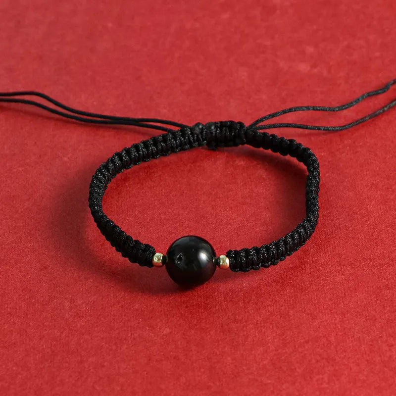 Woven red rope bracelet with spherical strawberry quartz or obsidian beads and an alloy clasp.