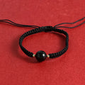 Woven red rope bracelet with spherical strawberry quartz or obsidian beads and an alloy clasp.