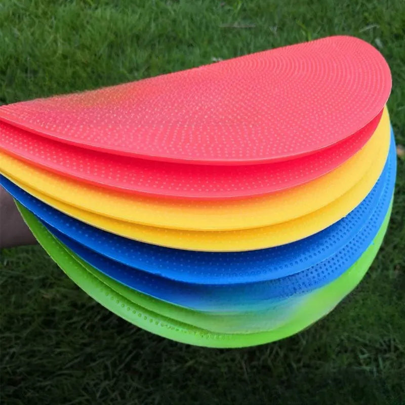 Soft TPE football training marker pad in assorted colours on grass, 23cm diameter.
