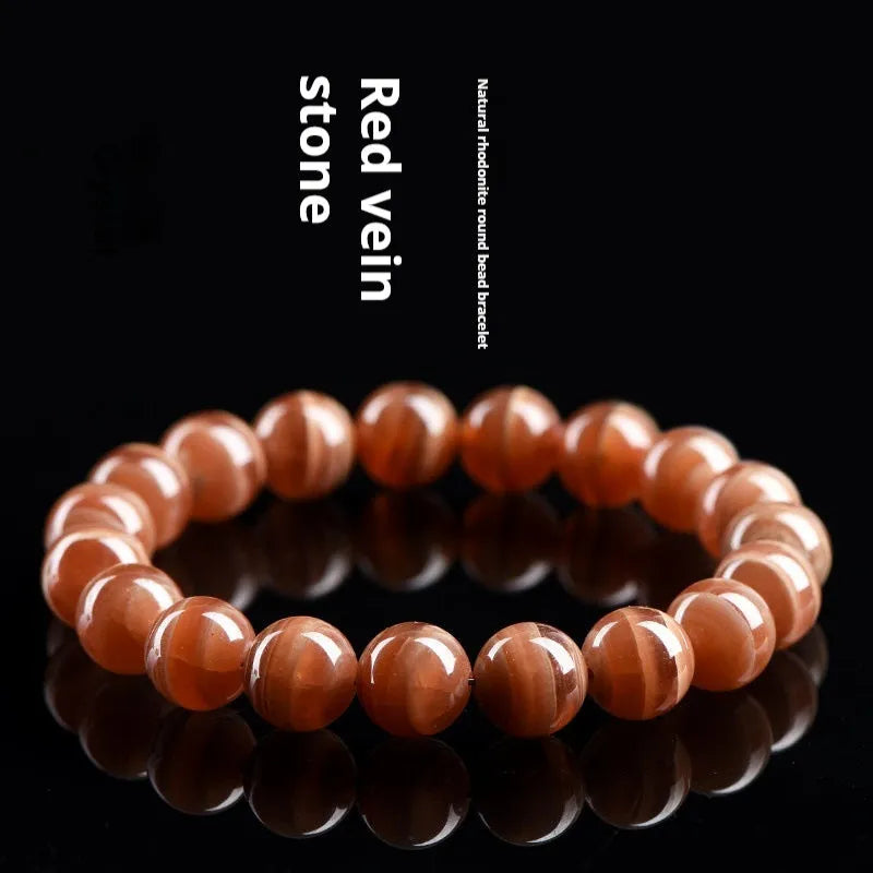 Natural old mine rhodochrosite bracelet with geometric beads and Ruyi symbols on a wrist.