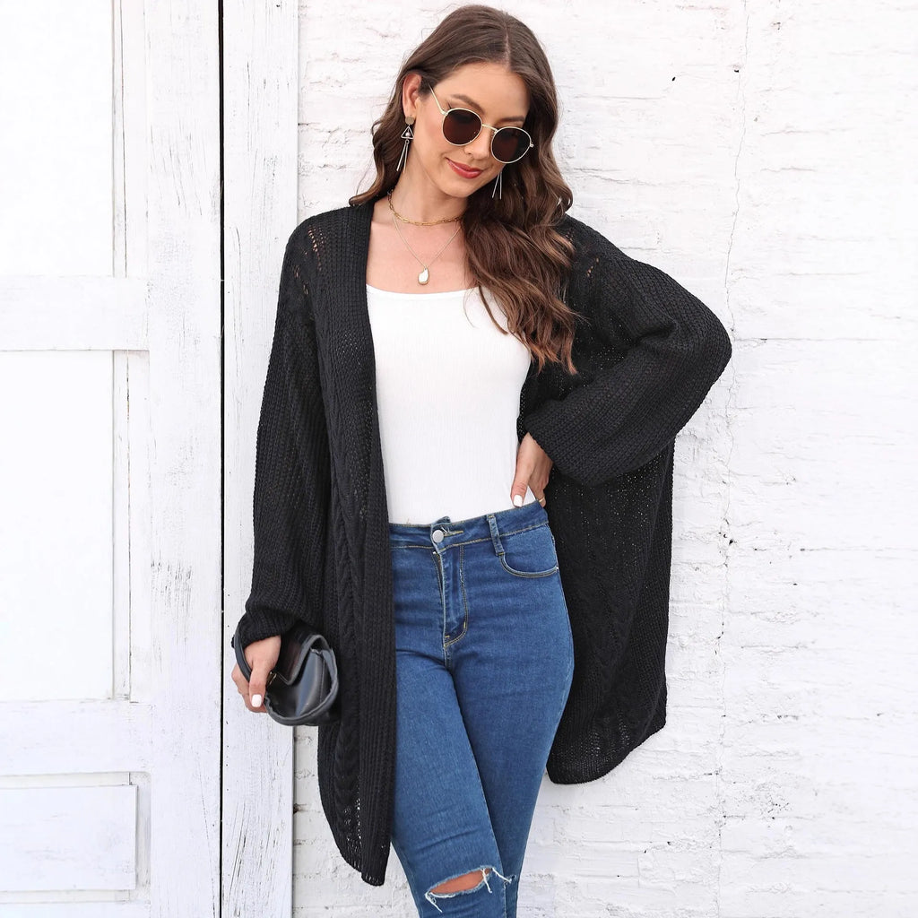 A women's loose-fitting solid colour acrylic sweater coat on a hanger.