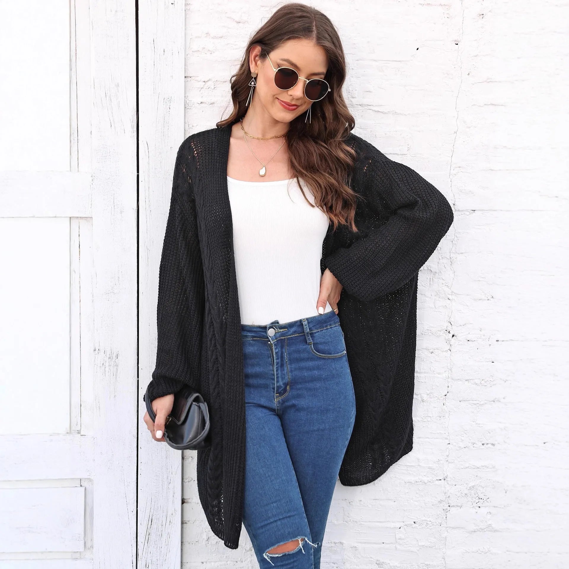 A women's loose-fitting solid colour acrylic sweater coat on a hanger.