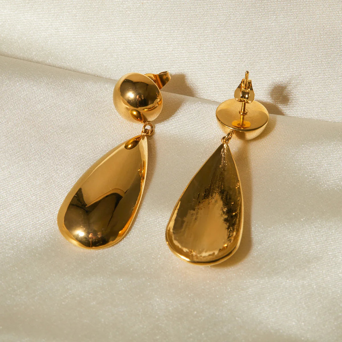 A pair of gold-coloured hemisphere-shaped earrings with a water drop pendant design, made from stainless steel.
