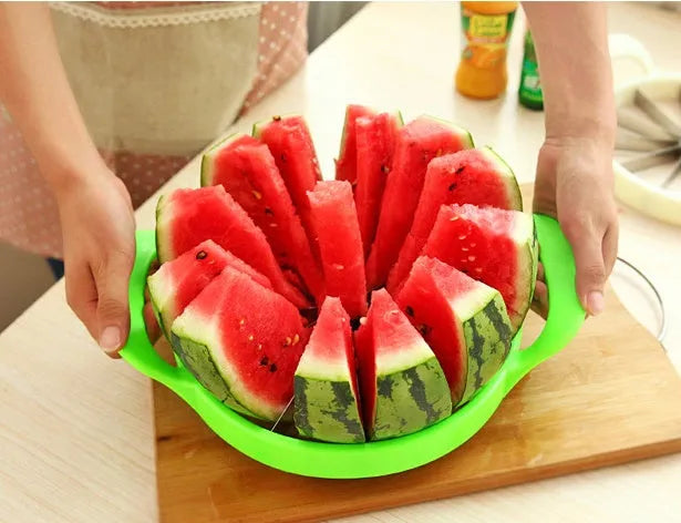 Green plastic melon slicer with stainless steel blades cutting a watermelon into wedges.