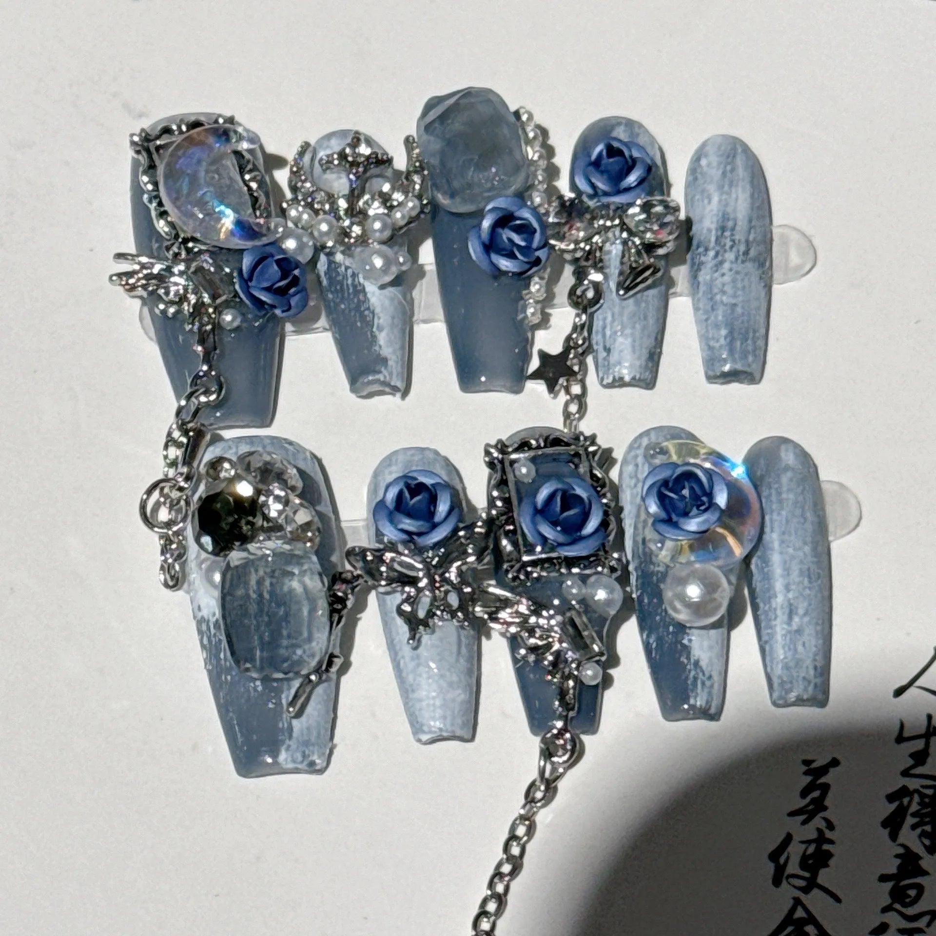 False nails with ornate rose and floral pattern in dark blue, showing sizes XS, S, M, L.