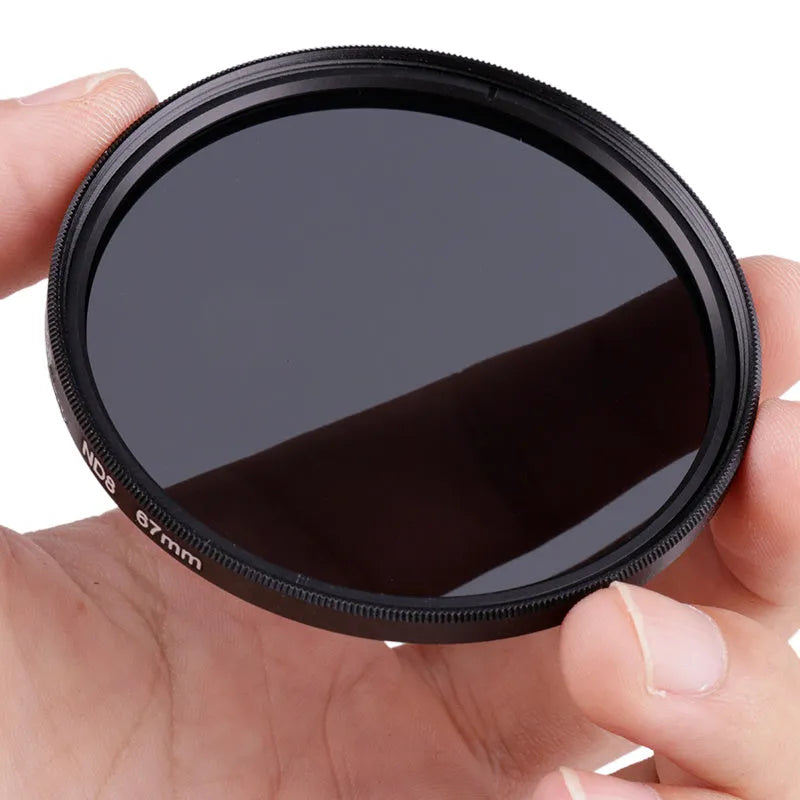 ND8 neutral density camera filter with aviation aluminium frame shown next to a lens.