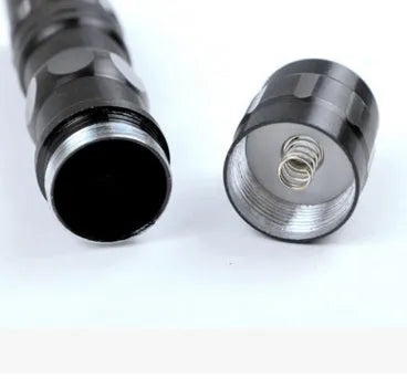 Compact black aluminium LED mini flashlight with keyring, shown next to a AA battery for scale.
