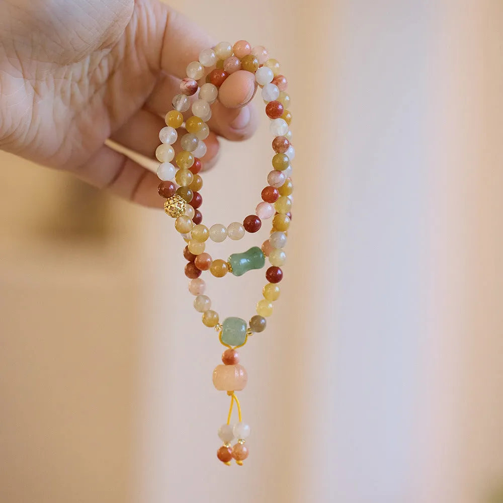 Handmade women's Jinsi Jade bracelet with three pumpkin beads and tassel on a wrist.
