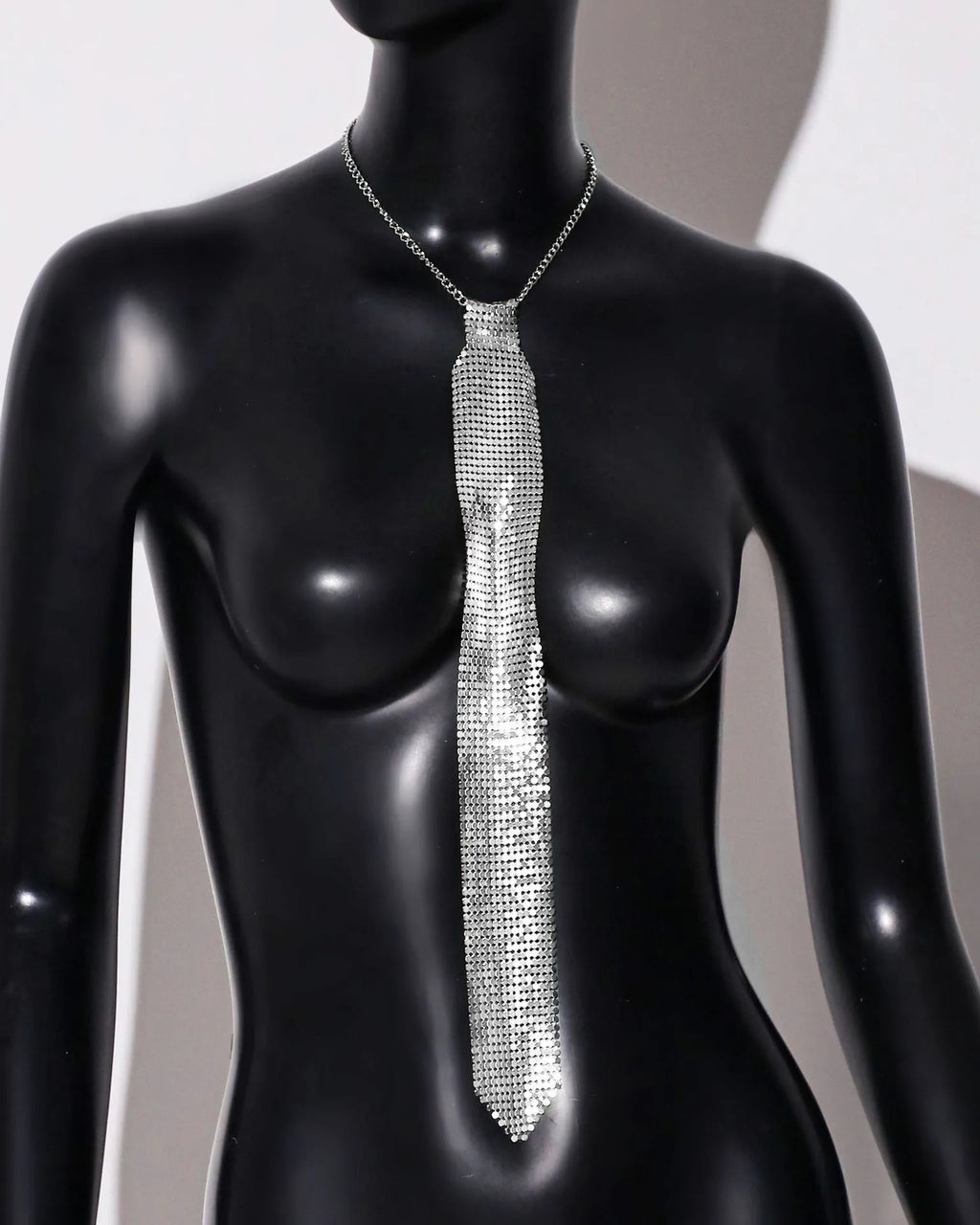 Silver metal sequin bow tie with arrow-style pointed ends on a black background