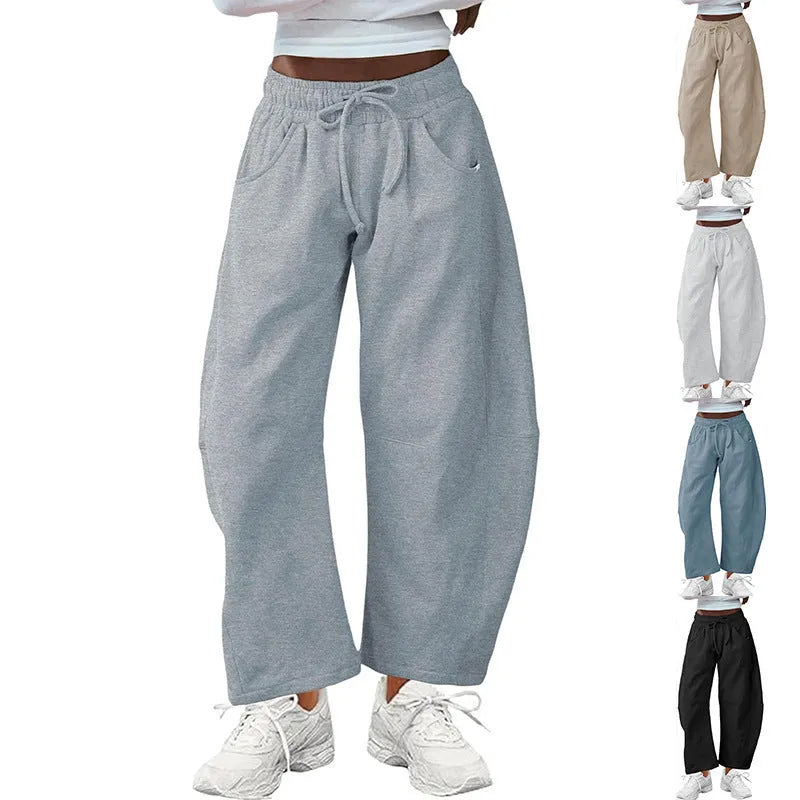 Woman wearing loose light grey cropped sweatpants with drawstring waist and side pockets