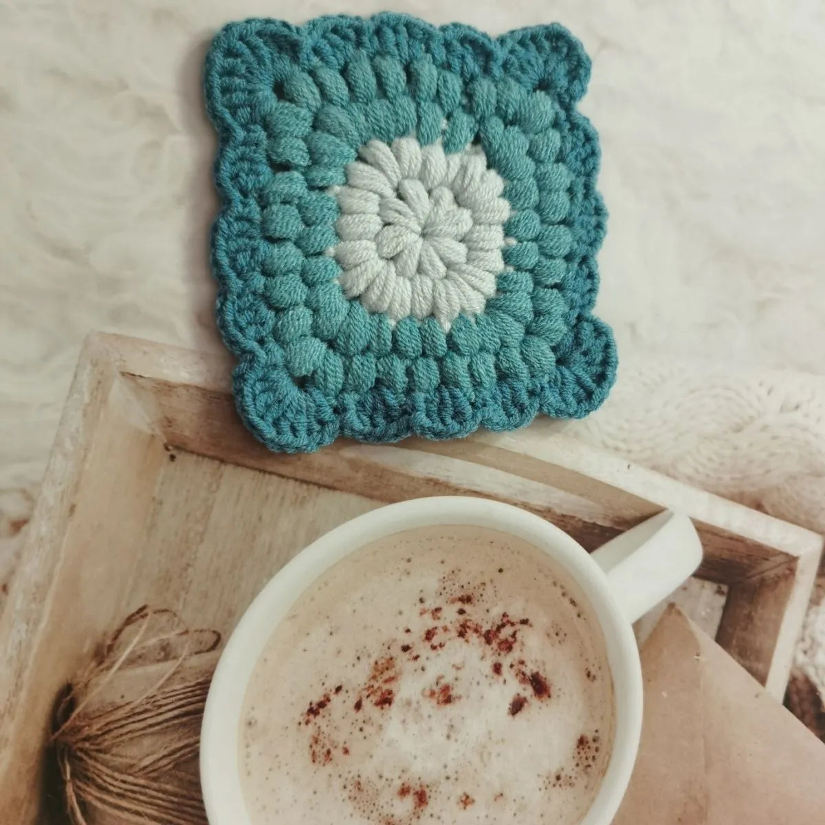 Crocheted wool cup placemat with grandmother lattice pattern in a choice of four colours.