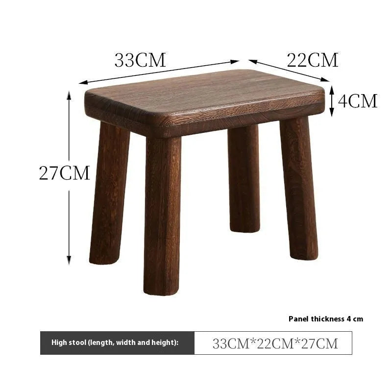 Distressed solid wood shoe stool with bracket legs in a living room setting.