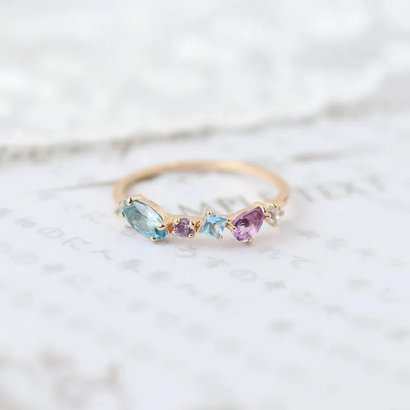 Gold-plated geometric ring with inlaid topaz and white amethyst stones on a white background