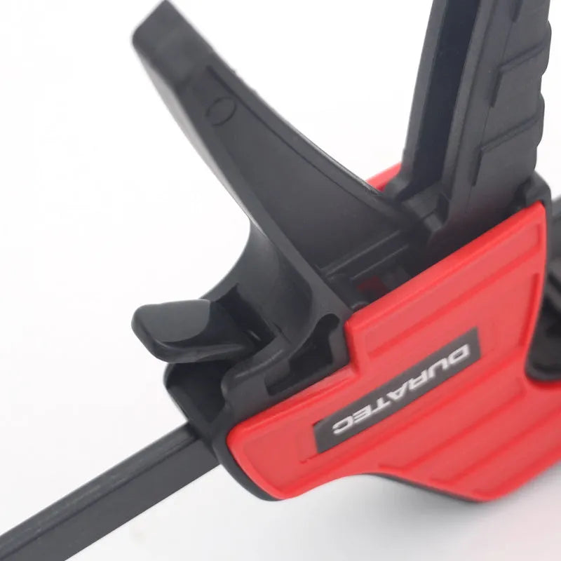 Black plastic one-handed ratcheting woodworking clamp with a quick-release trigger and soft rubber protective grips.
