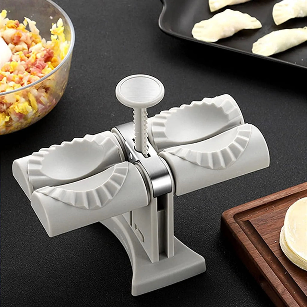 White double-head manual dumpling mould with stainless steel and plastic construction on a rubber anti-slip mat.