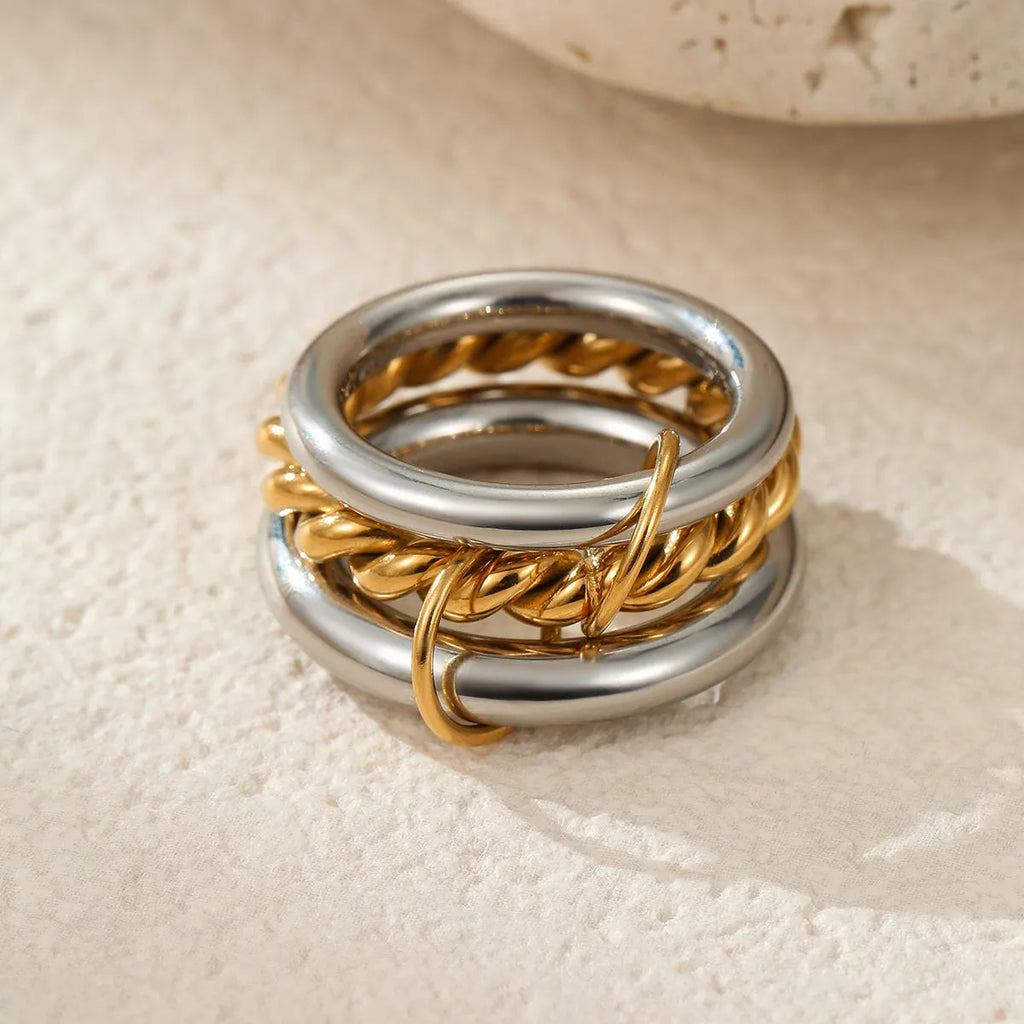 Stacked gold plated stainless steel ring set for women in an exaggerated style on a hand.