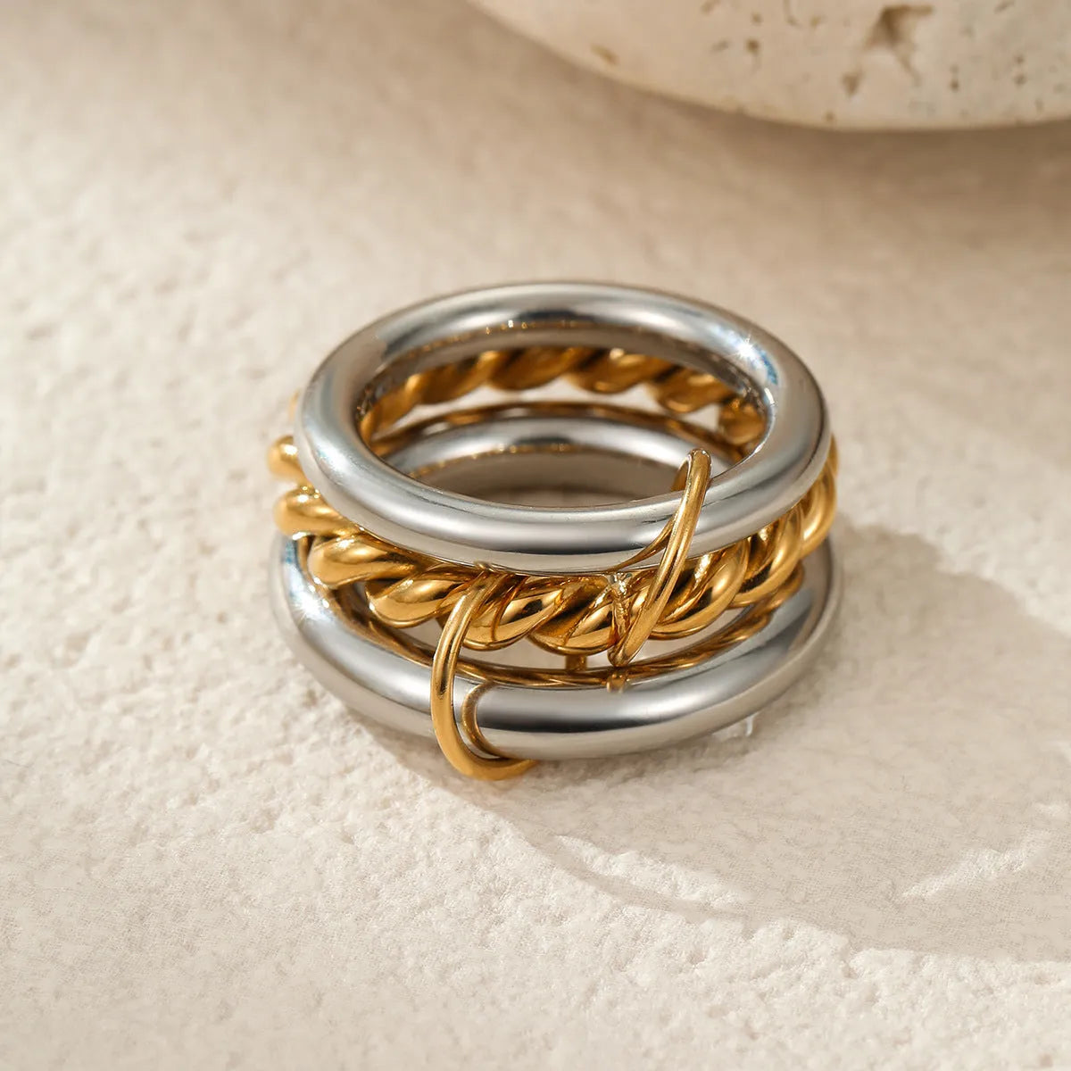 Stacked gold plated stainless steel ring set for women in an exaggerated style on a hand.