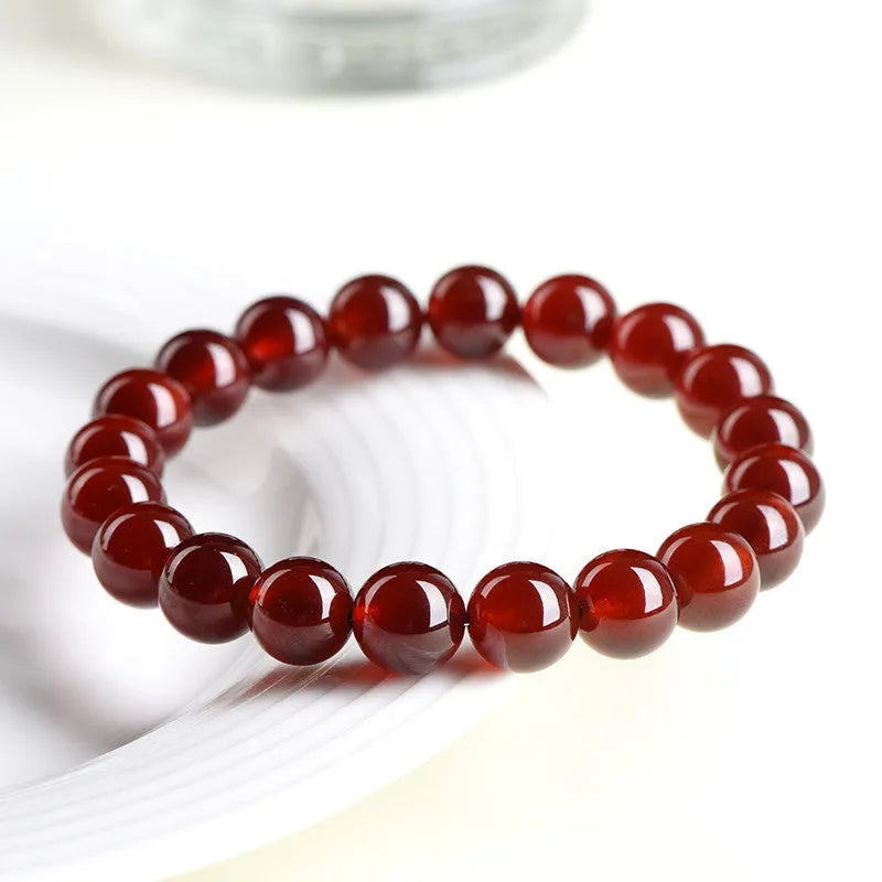 Natural orange red garnet ball bracelet with a traditional Ruyi-style clasp on a wrist.