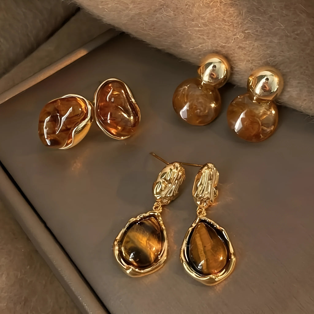 Handmade geometric alloy earrings with tassel details in three styles: round piece, irregular amber, and water drop tiger eye studs
