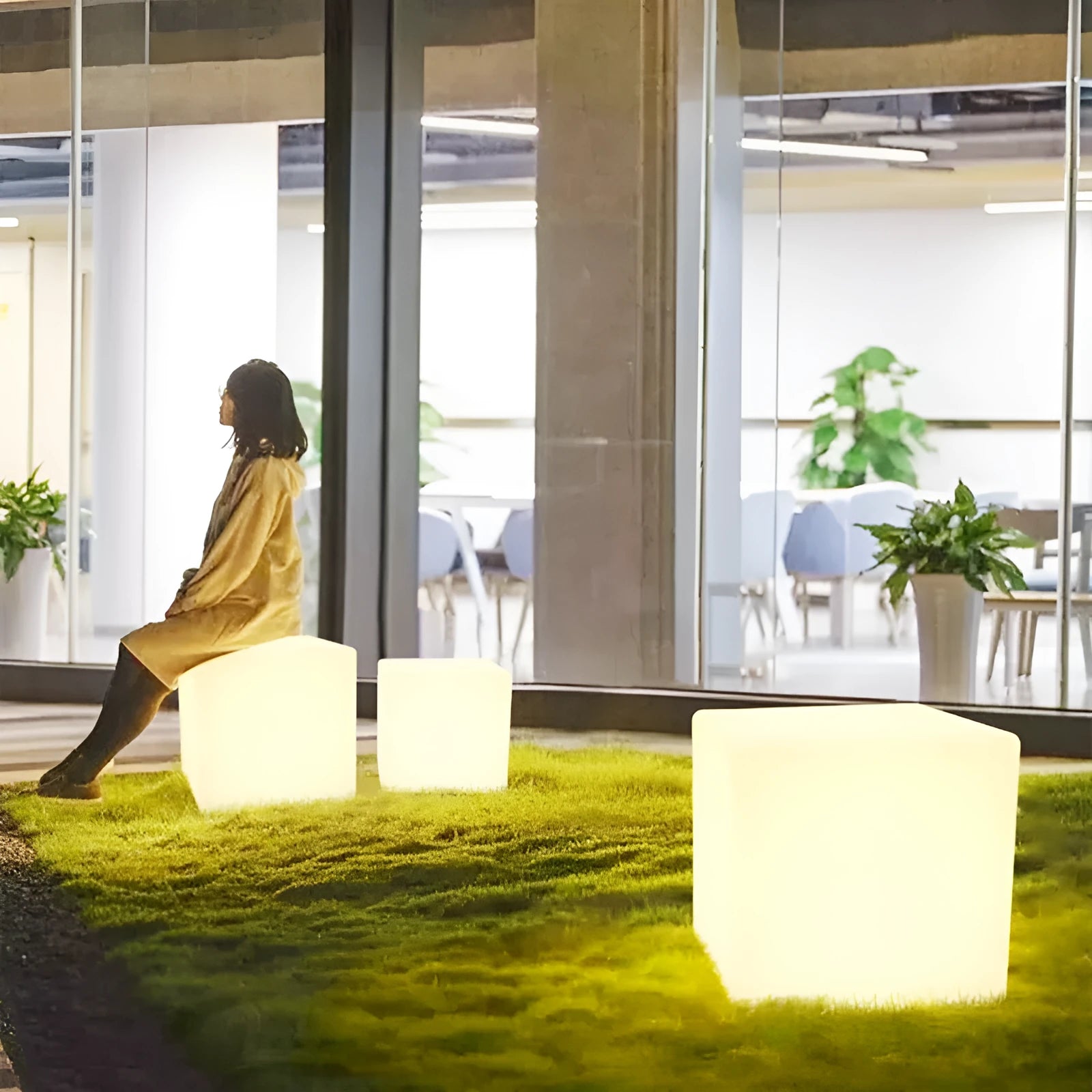 Modern square LED cube light stool in outdoor garden setting showing waterproof IP65 construction