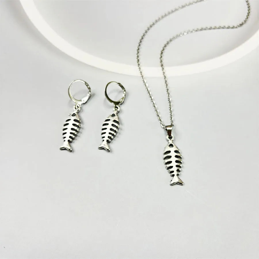 Close-up of silver fishbone pendant earrings on a white background, showing O-shaped chain detail.