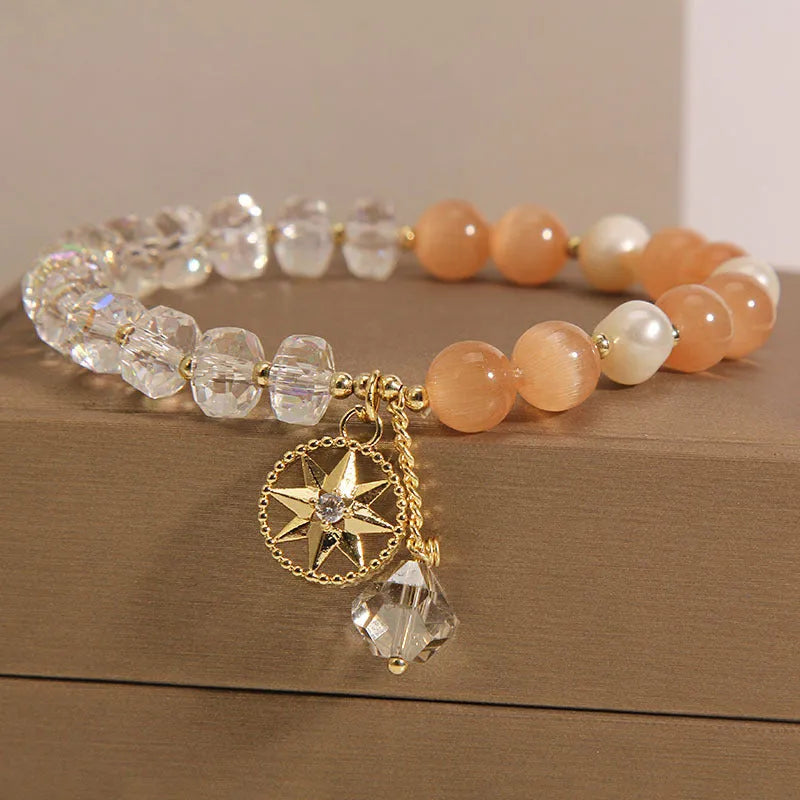 Women's gold-plated bracelet with an eight-pointed star design and a central inlaid orange opal crystal.