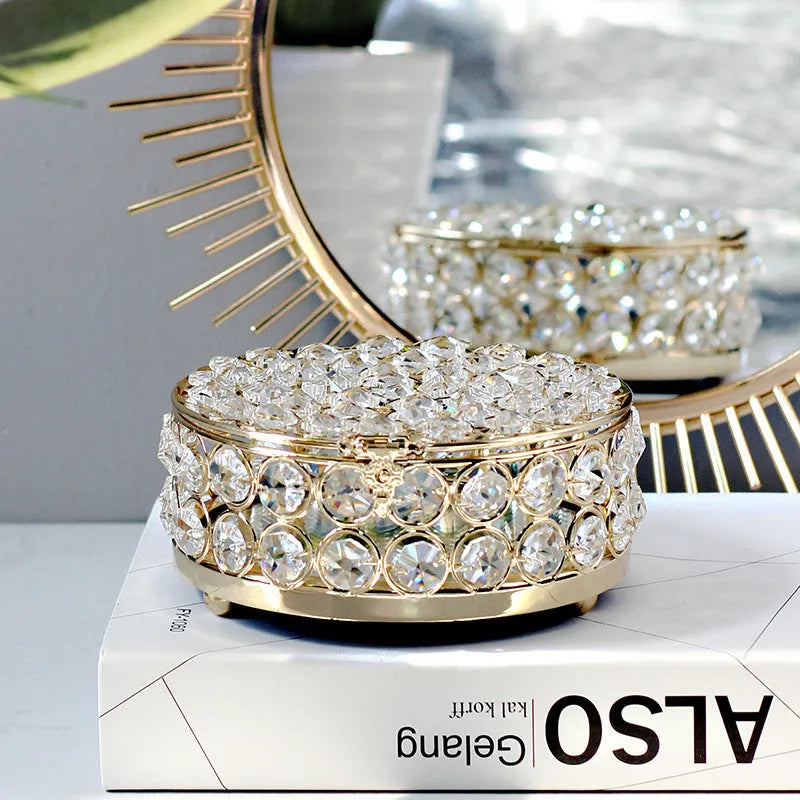 French gold metal jewelry box with a clear crystal glass lid and a lock, shown on a surface.