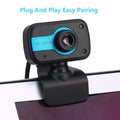 Blue mini USB webcam with a 360-degree rotating head on a desk next to a laptop.