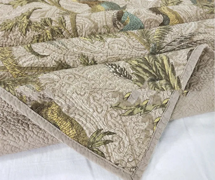 Blue American floral and bird pattern quilted cotton bedspread set laid on a bed.