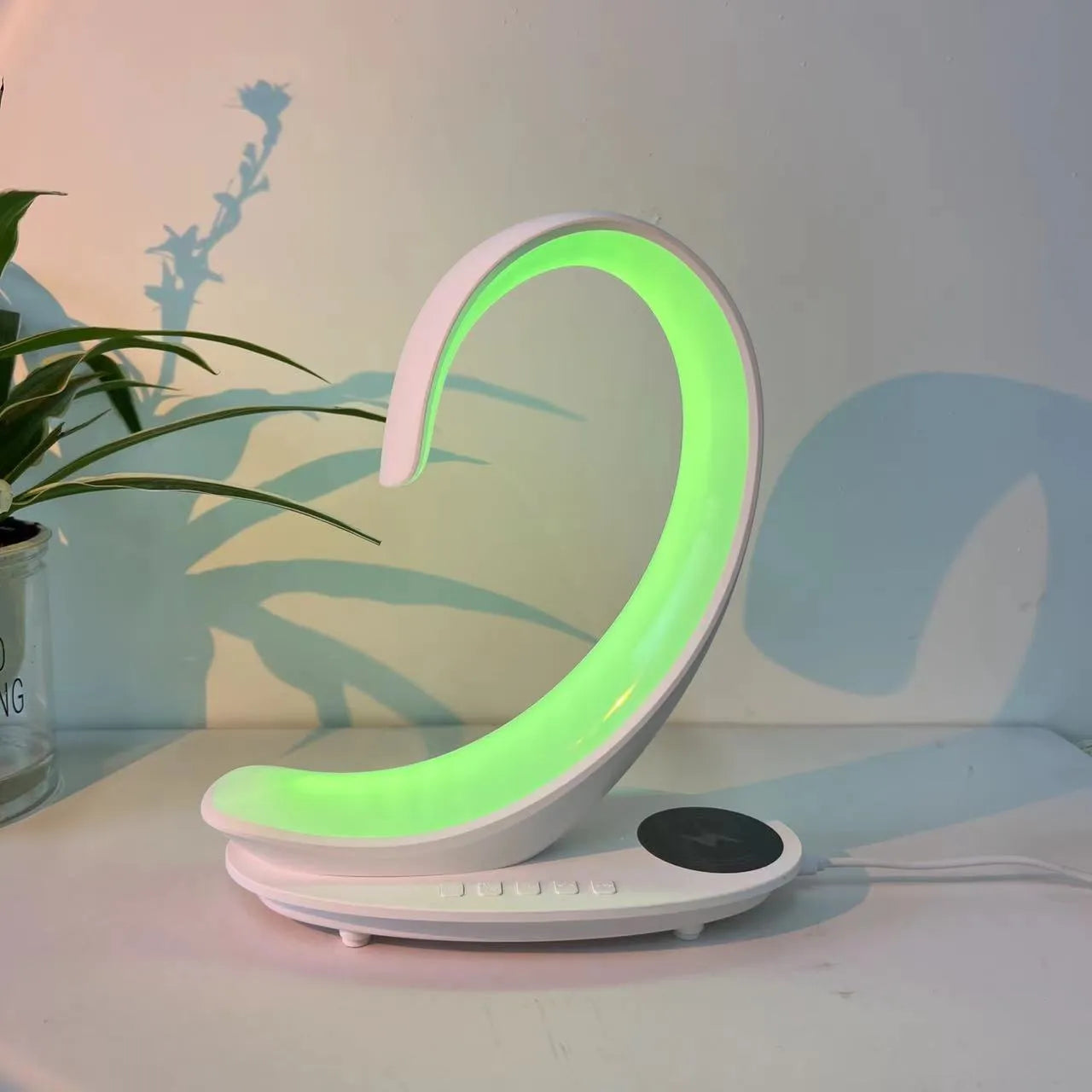 White swan sculpture desk lamp with integrated wireless phone charger and Bluetooth speaker emitting colourful light.