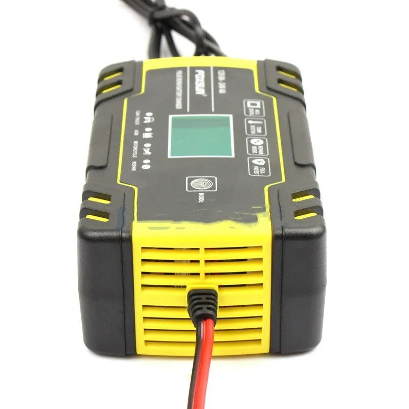 12V 24V vehicle battery charger with digital display and UK plug on a workbench.