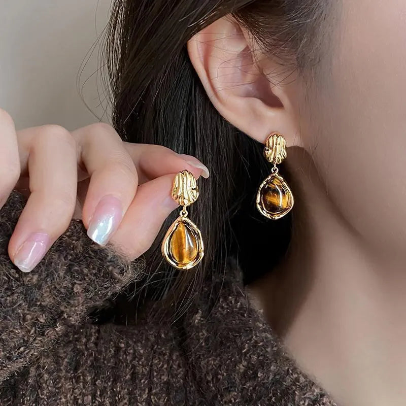 Handmade geometric alloy earrings with tassel details in three styles: round piece, irregular amber, and water drop tiger eye studs