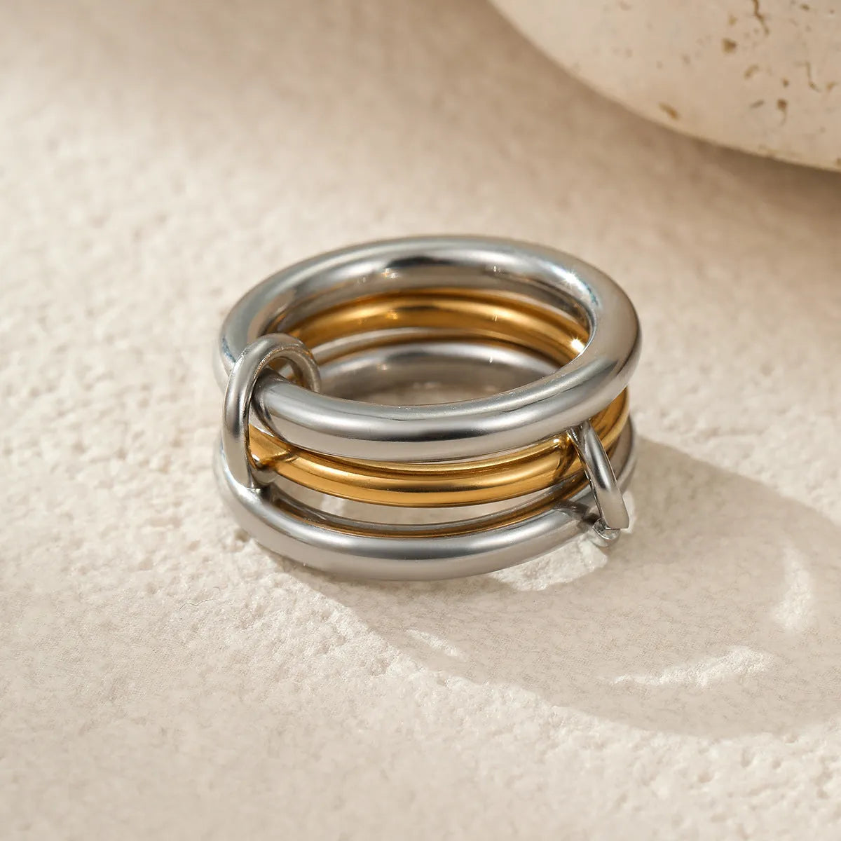 Stacked gold plated stainless steel ring set for women in an exaggerated style on a hand.