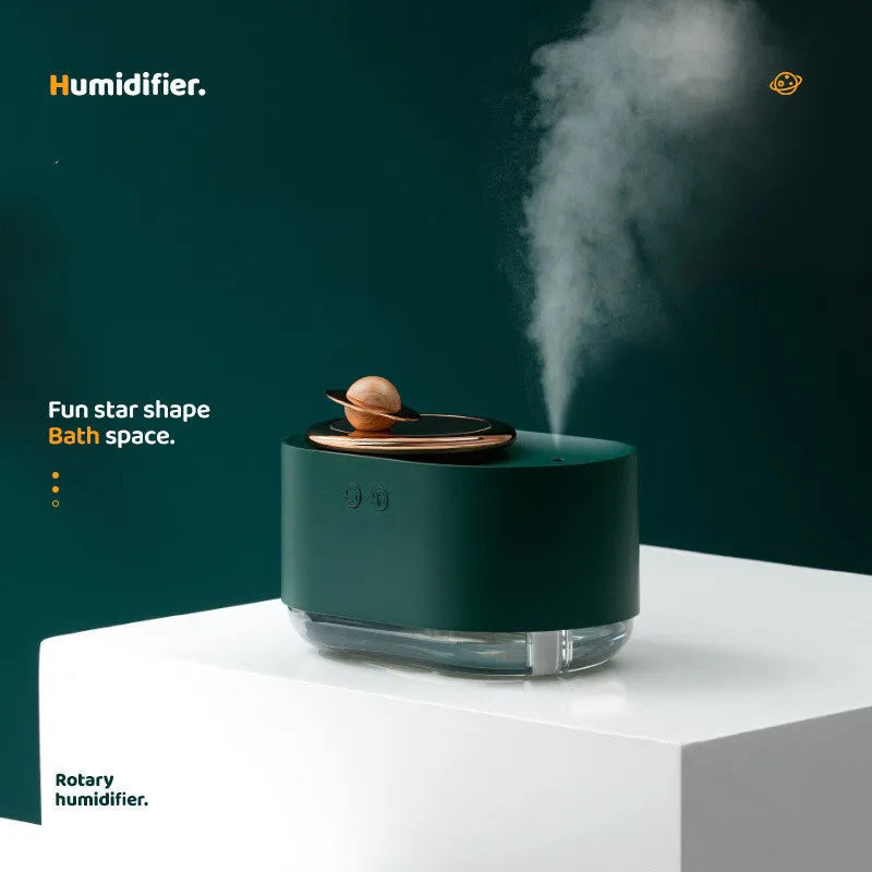 Green rotating planet shaped car humidifier with night light on a desk next to a USB cable.