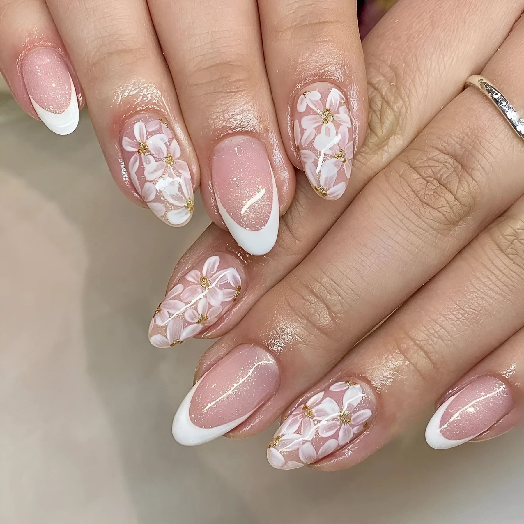 Short glossy almond artificial nails with French tip and glitter flower decorations