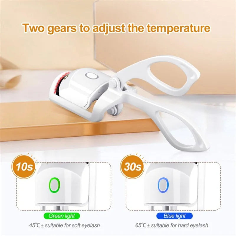 White USB rechargeable heated eyelash curler with dual temperature lights, shown next to its charging cable.