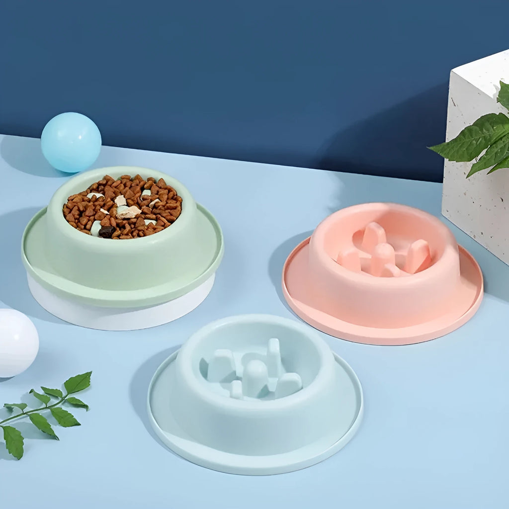 Blue pet slow feeder bowl with raised obstacles on a kitchen floor.