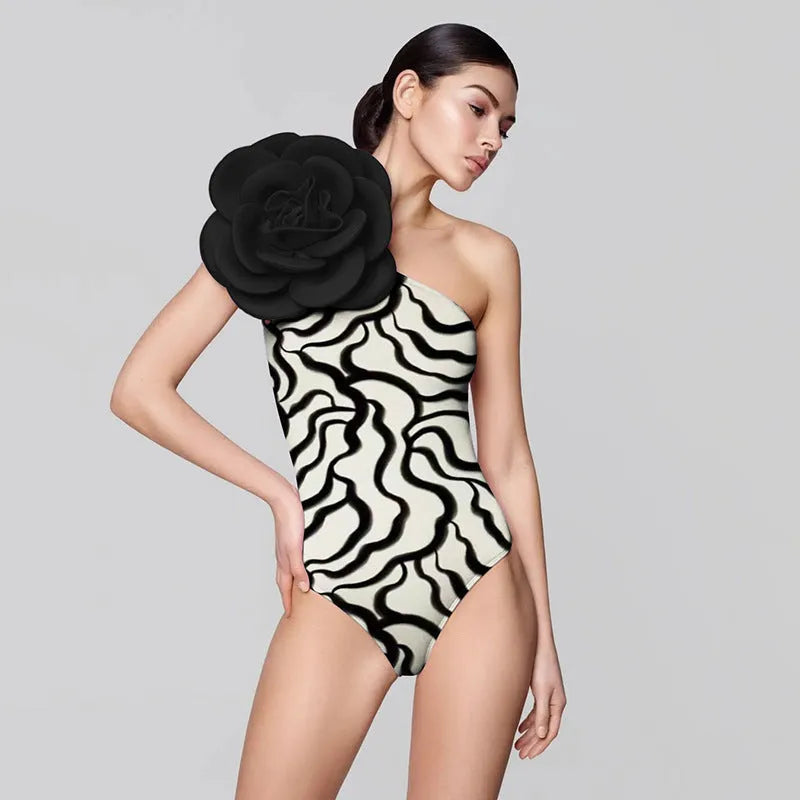 Black one-piece swimsuit with three-dimensional white floral pattern on a mannequin.