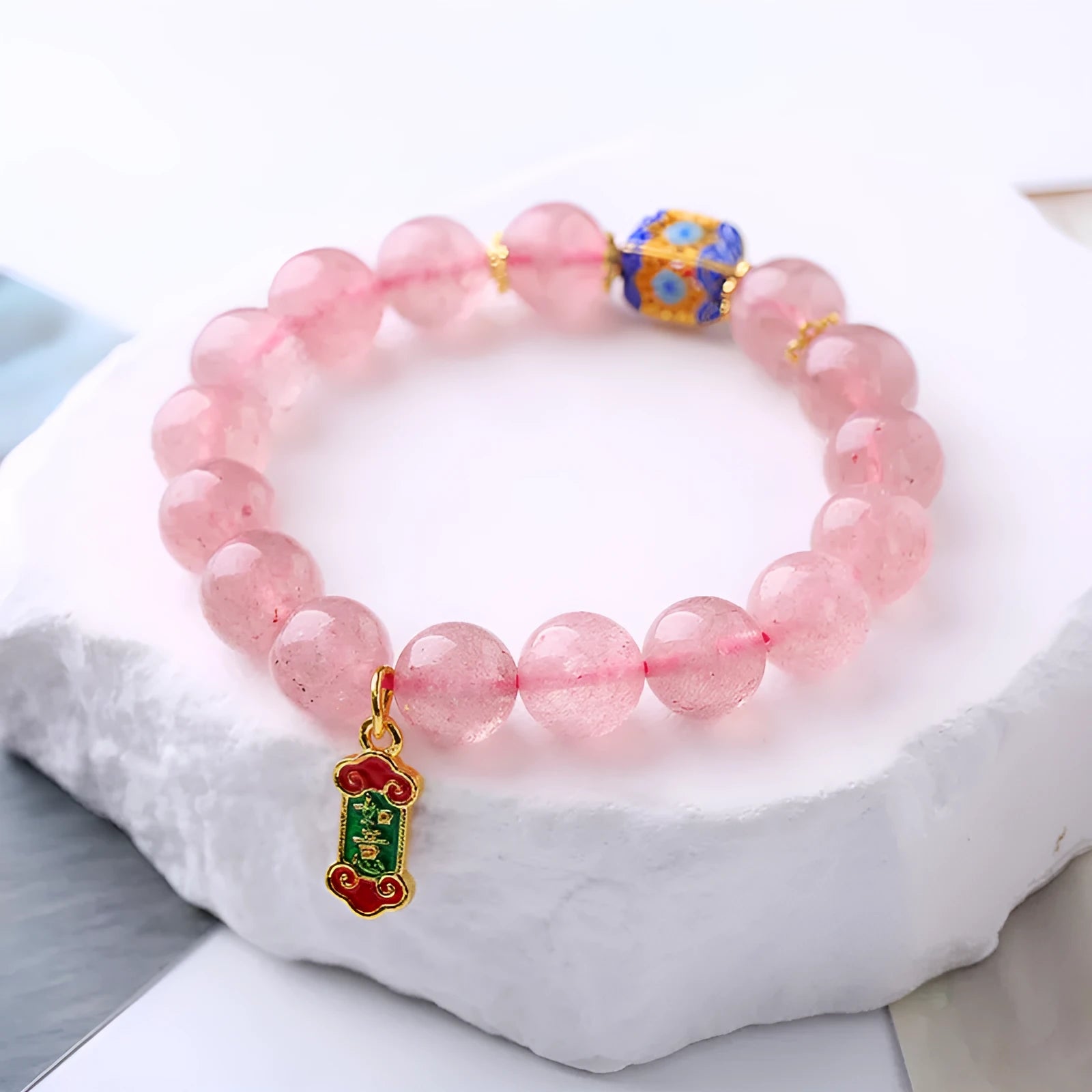 Close-up of hand-woven pink strawberry quartz crystal bracelet with Ruyi motif design