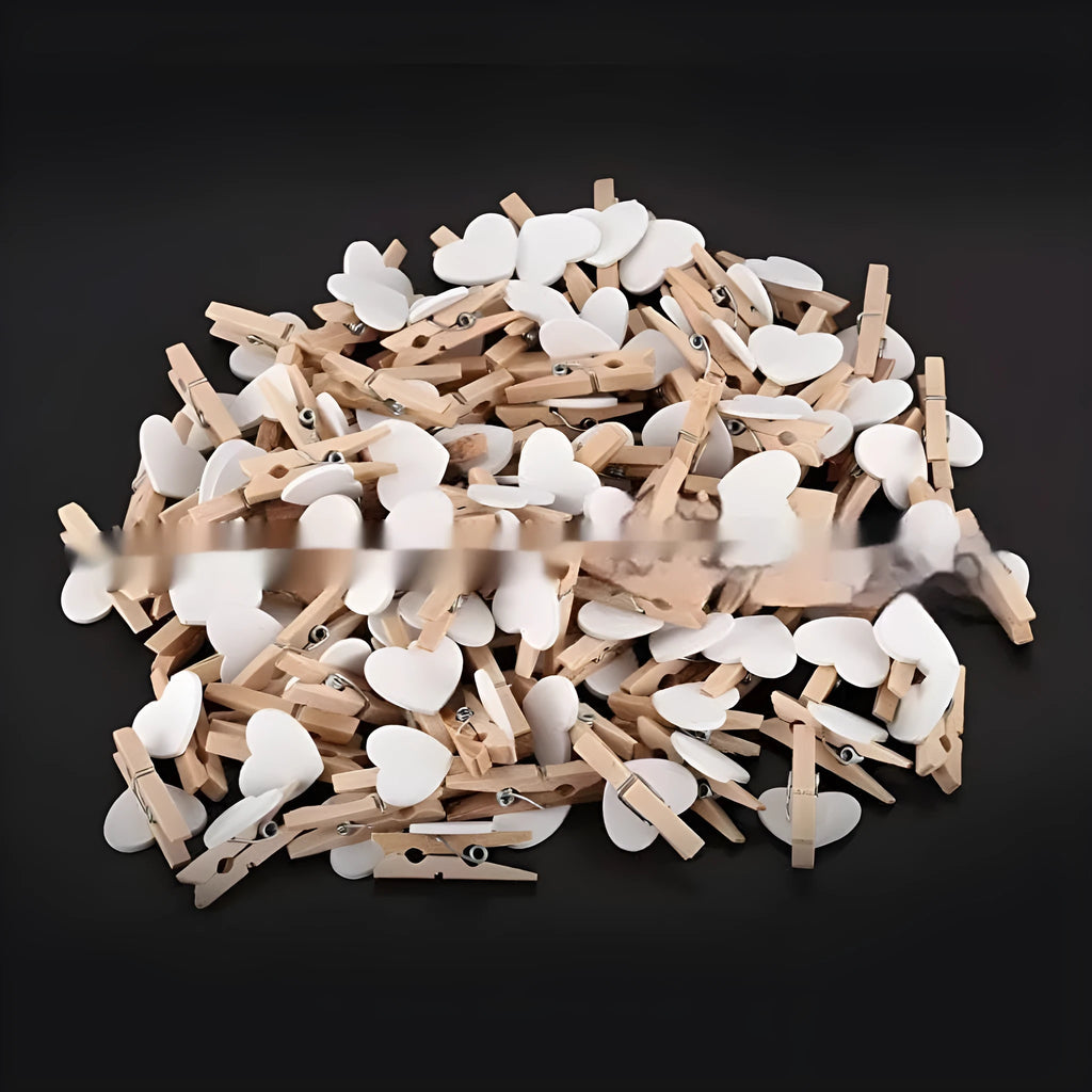 Five handmade wooden heart-shaped clips in red, white, and rose red on a surface.