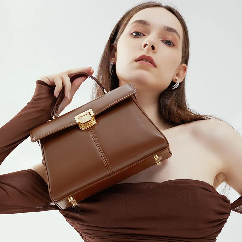Women's black leather shoulder bag with a vachette clasp, showing its horizontal square shape and adjustable strap.