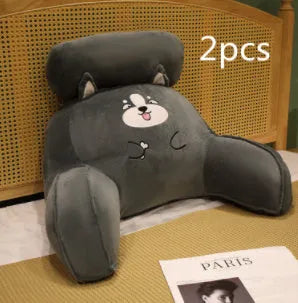 Grey triangle-shaped reading pillow with embroidery on a chair, showing its ergonomic back support shape.