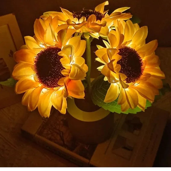 Rechargeable artificial sunflower LED table lamp with USB cable on wooden surface.
