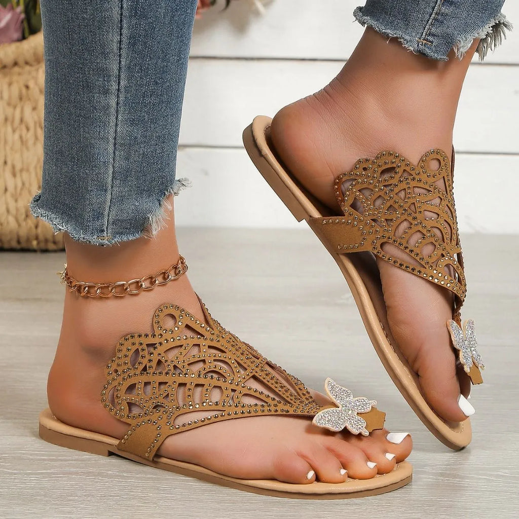 Women's black slip-on sandals with rhinestone decoration and a flip-toe design on a flat rubber sole.