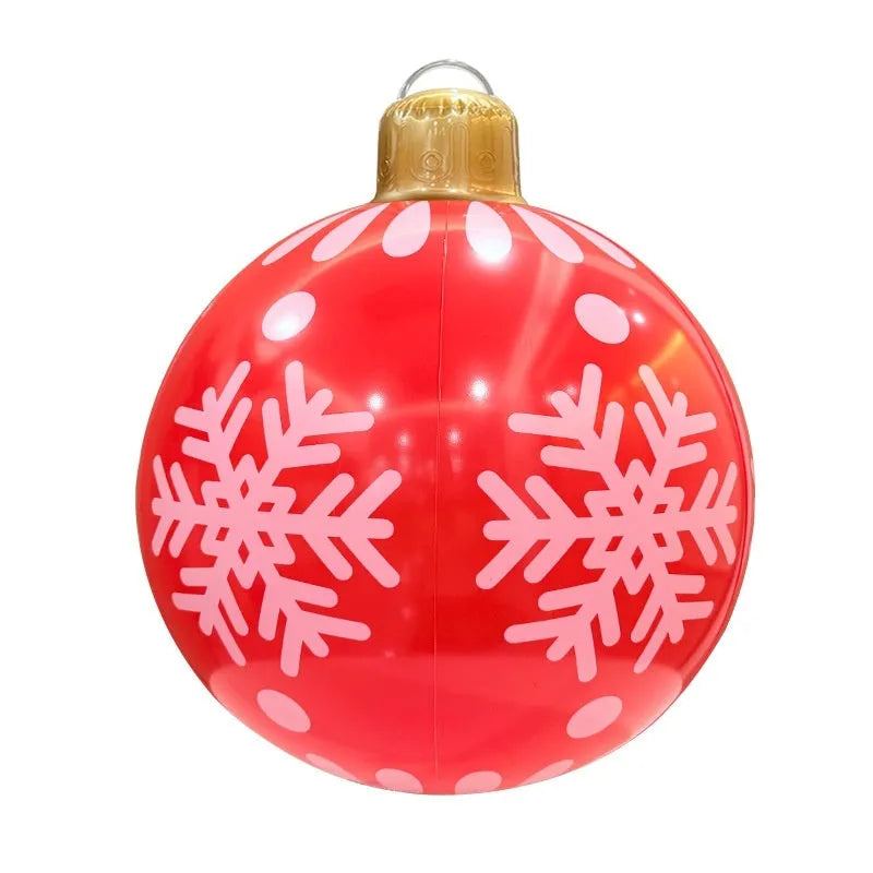 Large red and white inflatable Christmas ball with snowflake design and LED lights in a garden
