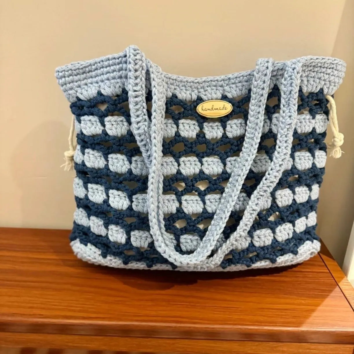 Handmade woven shoulder bag with a floral pattern, made from soft wool yarn.