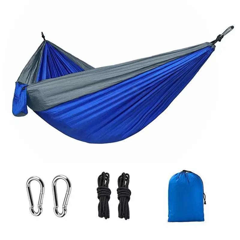 Blue parachute nylon camping hammock hung between two trees showing its full 270cm length.